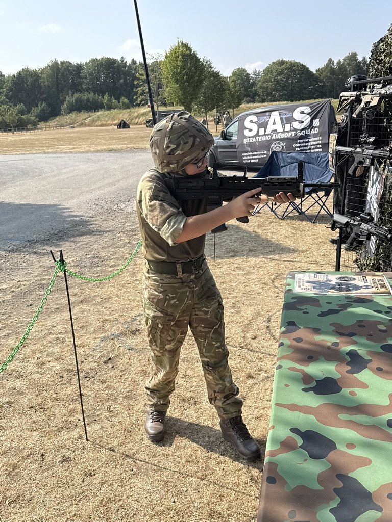 A range marshal taking aim with a pistol beside the S.A.S. banner